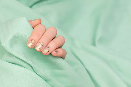 Female hand with clear nail design. Glitter clear nail polish manicure with green nail art. Woman...