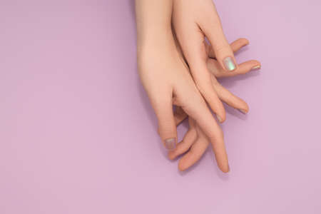 Female hands with pearlescent nail design. Glitter pearlescent nail polish manicure. Female model hands with perfect nails on pink background. copy spaceの写真素材