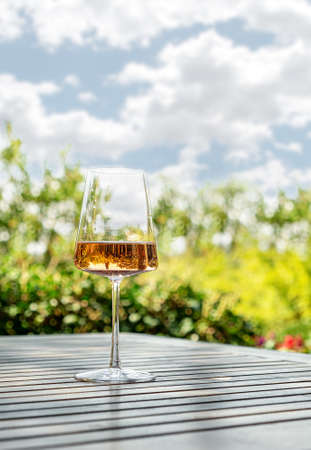 Glass of tasty wine on a wooden table in spring italian garden with perfect view. Outdoor wine tasting in Italyの写真素材