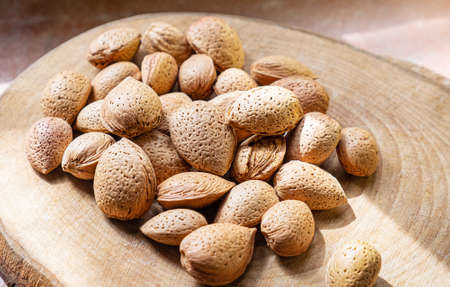 Pile of raw almonds nuts of a wooden background. Raw organic almond nut on a wooden circle cut