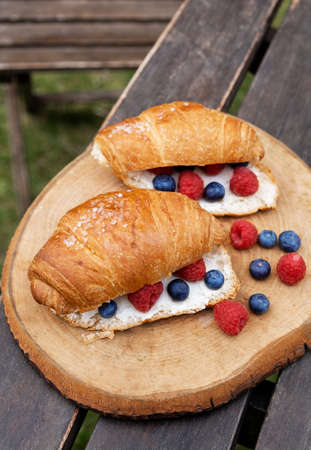 Fresh croissants with cream cheese and berries. Tasty croissants with ripe berries: blueberry and...