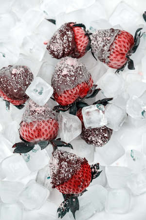 Fresh strawberries dip in chocolate dip with nuts on ice. Cold fresh strawberry in milk chocolate. Berries in chocolateの写真素材