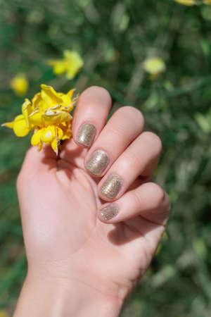 Female hand with summer nail design. Glitter gold nail polish manicure. Female model hand with...
