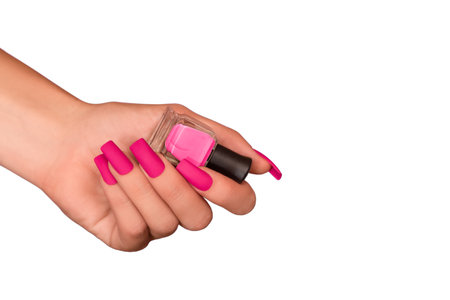 Female hand with pink nail design. Mate pink nail polish manicure. Female model hand with perfect manicure hold pink nail polish bottle on white background. Copy space. Place for text.の写真素材