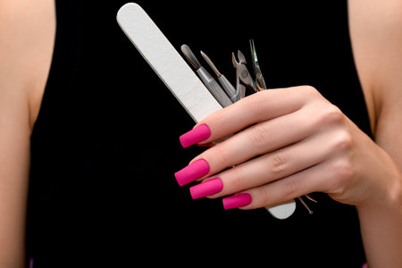 Female hand with pink nail design. Mate pink nail polish manicure. Female model in black dress with perfect pink manicure hold manicure set.の写真素材