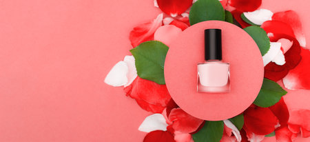 Glitter red nail polish bottle in a circle rose petals and leaves on red background. Red nail polish bottle with copy space place. Nail polish conceptの写真素材