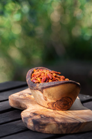 Hot spicy chili pepers. Close up of dried red dry chili pepers in a wooden bowl on a wooden desk. Hot chili pepers for seasoning. Asian and Mexican food spices.の写真素材