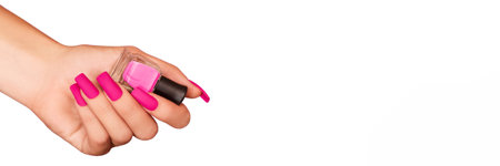 Female hand with pink nail design. Mate pink nail polish manicure. Female model hand with perfect manicure hold pink nail polish bottle on white background. Copy space. Place for text. Banner ad. Advertising banner template.の写真素材