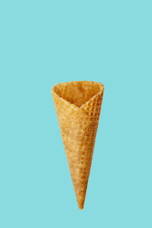 Wafer sugar cone on a blue background. Waffle cone on blue background. Empty waffle cone on blue...
