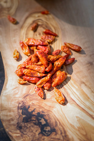 Hot spicy chili pepers. Close up of dried red dry chili pepers on a wooden board. Hot chili pepers for seasoning. Asian and Mexican food spices.の写真素材