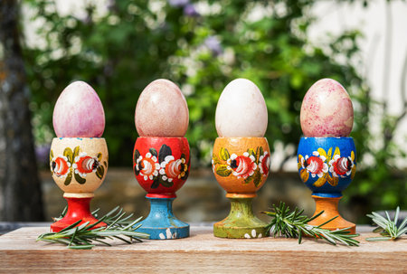 Easter eggs in a wooden decorated egg stand in the garden closeup. Christian Easter painted eggs in a wooden egg stand with rosemary. Springtime holiday - Easter.の写真素材