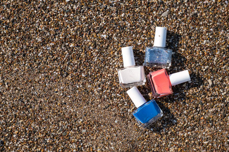 Collection of nail polish of pastel colors in unlabeled bottels on wet beach pebbles. Summer beauty mockup.の写真素材