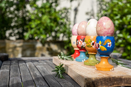 Easter eggs in a wooden decorated egg stand in the garden closeup. Christian Easter painted eggs in a wooden egg stand with rosemary. Springtime holiday - Easter.の写真素材