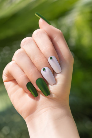 Female hand with summer long nail design. Summer nail polish manicure with rhinestones nail art. Female hand with perfect nails on tropical background. Tropic manicure for postcard, poster or bannerの写真素材