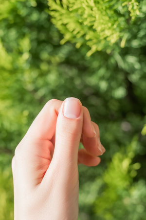 Nails background. Female thumb on green leaves background. Female thumb with nude manicure. Thumb manicure on floral background.の写真素材