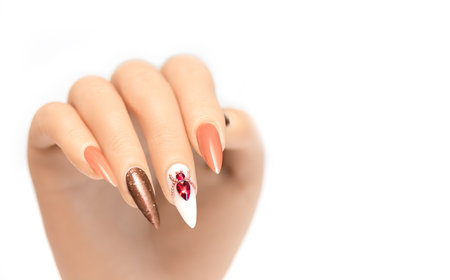 Female hand with stiletto nail design. Glitter orange nail polish manicure with orange rhinestones spider nail art. Female model hand on white background. Copy spaceの写真素材