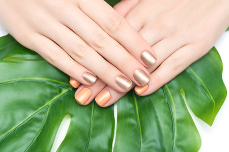 Nail design background. Nail art postcard. Female hands with gold and orange nail design. Gold glitter manicure. Orange glitter manicure. Copy space. Place for text.の写真素材