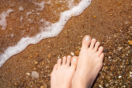 Female feet on ocean beach close up. Vacation holidays. Woman feet closeup on beach at summer day. Vacation backgroundの写真素材