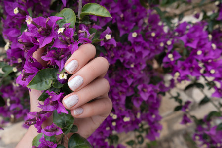Female hand with tropical nail design. Glitter white nail polish manicure. Female model hand with perfect manicure.の写真素材