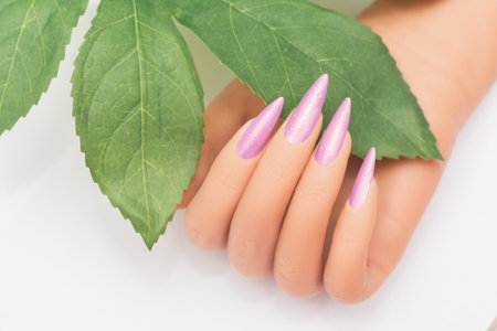 Female hand with stiletto nail design. Pink glitter nail polish manicure. Female hand with perfect manicure on white backgroundの写真素材