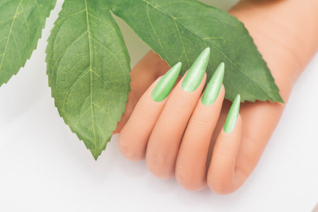 Female hand with stiletto nail design. Glitter green nail polish manicure. Female hand with perfect manicure on white backgroundの写真素材