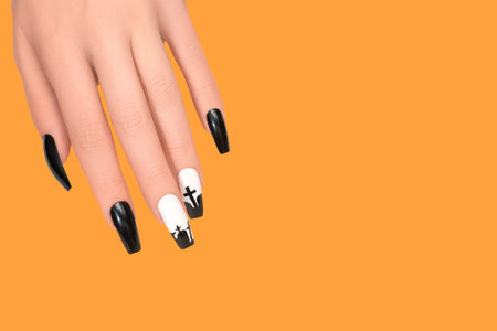 Halloween nail design black white color with cross. Female hand with autumn manicure, top view. Halloween conceptの写真素材