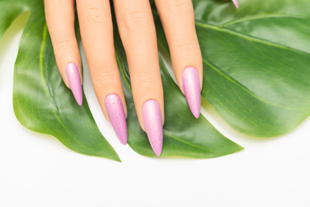 Female hand with stiletto nail design. Glitter pink nail polish manicure. Female hand with perfect manicure on white backgroundの写真素材
