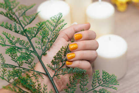 Female hand with yellow nail design. Glitter yellow nail polish manicure. Female model hand with perfect manicure.の写真素材