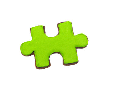 Cookie in the form of a puzzle piece in bright green color on a white background.の写真素材