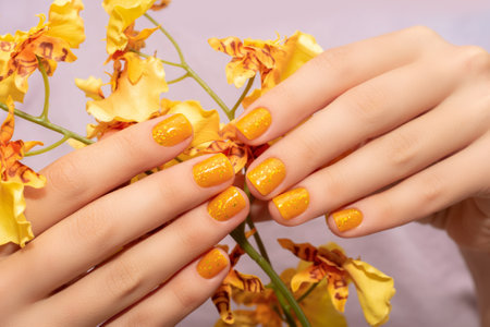 Female hand with yellow nail design. Glitter yellow nail polish manicure. Female model hand with perfect manicure.の写真素材