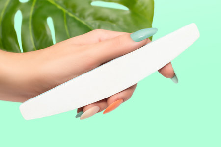 Female hands with glitter nail polish. Green and orange nail design with two shades. Women hands with sparkle colored manicureの写真素材