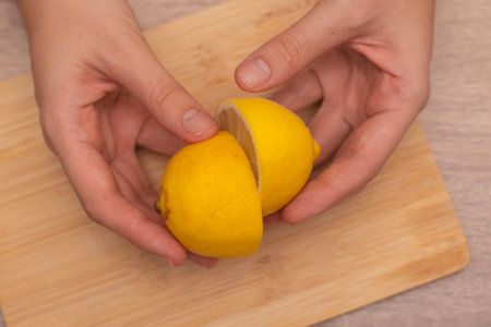 Hands Showcasing Half a Lemons. A person's fingers displaying a bright lemon halfの写真素材