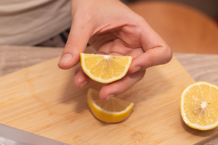 Hand Showcasing Half a Lemon. A person's fingers displaying a bright lemon halfの写真素材