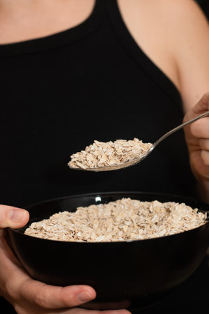 Serving Oats with a Spoon. Scooping oats from a bowl with a metal spoonの写真素材