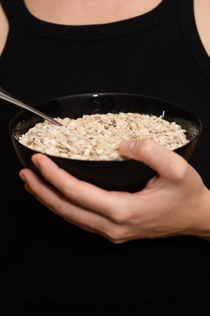 Serving Oats with a Spoon. Scooping oats from a bowl with a metal spoonの写真素材