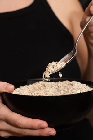 Serving Oats with a Spoon. Scooping oats from a bowl with a metal spoonの写真素材