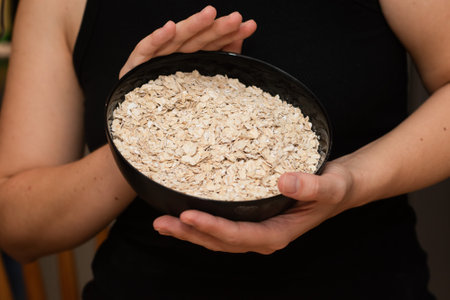 Holding a Bowl Full of Rolled Oats. Hands securely holding a bowl overflowing with whole rolled oatsの写真素材