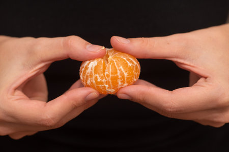 Peeling a Fresh Orange Mandarin. Female Hands skillfully exfoliating a juicy ripe mandarinの写真素材