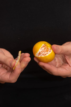 Peeling a Fresh Orange Mandarin. Female Hands skillfully exfoliating a juicy ripe mandarinの写真素材