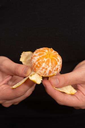 Peeling a Fresh Orange Mandarin. Female Hands skillfully exfoliating a juicy ripe mandarinの写真素材