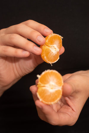 Peeling a Fresh Orange Mandarin. Female Hands skillfully exfoliating a juicy ripe mandarinの写真素材