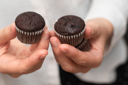 Hands Holding Chocolate Muffins. Presenting freshly baked chocolate muffinsの写真素材
