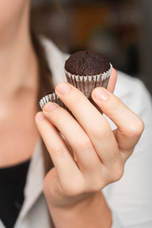 Hand Holding Chocolate Muffins. Presenting freshly baked chocolate muffinsの写真素材