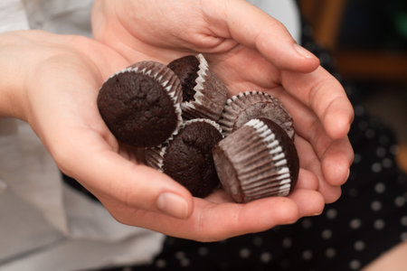 Hands Holding Chocolate Muffins. Presenting freshly baked chocolate muffinsの写真素材