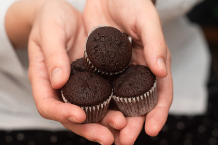 Hands Holding Chocolate Muffins. Presenting freshly baked chocolate muffinsの写真素材