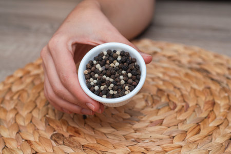 Bowl of Whole Peppercorns in a Female Hand. Gently holding a ramekin filled with assorted whole...