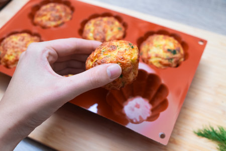 Savory Muffin in a female Hand. Hand selecting a golden-baked savory muffinの写真素材