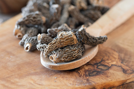 Dry Morel Mushrooms on Wooden Platter. Close-up of textured morel mushrooms, artfully arranged on a rustic wooden platter, emphasizing their unique structure.の写真素材
