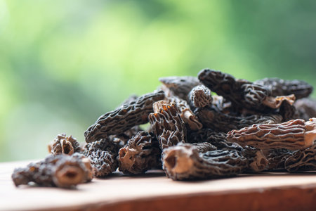 Dry Morel Mushrooms on Wooden Platter. Close-up of textured morel mushrooms, artfully arranged on a rustic wooden platter, emphasizing their unique structure.の写真素材