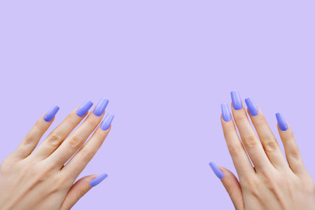 Green Nail Polish on Female Hands with Long Nails. Female hands with long, green nail polish on a matching green backgroundの写真素材